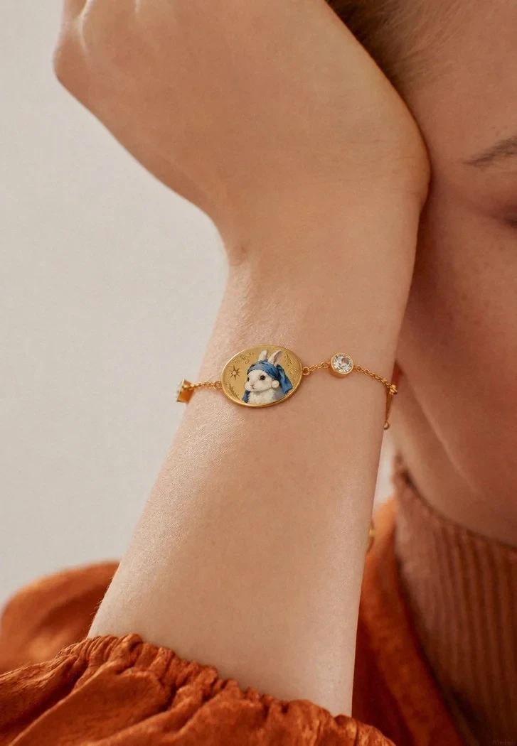 An oval hand-painted enamel bracelet worn on the wrist