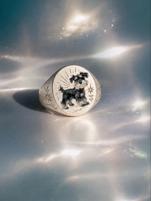 A hand-painted dog portrait signet ring photographed on its own